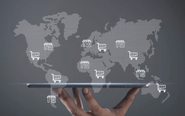 Mano sosteniendo una tablet con un mapa mundial y carritos de compra — cross-border eCommerce global