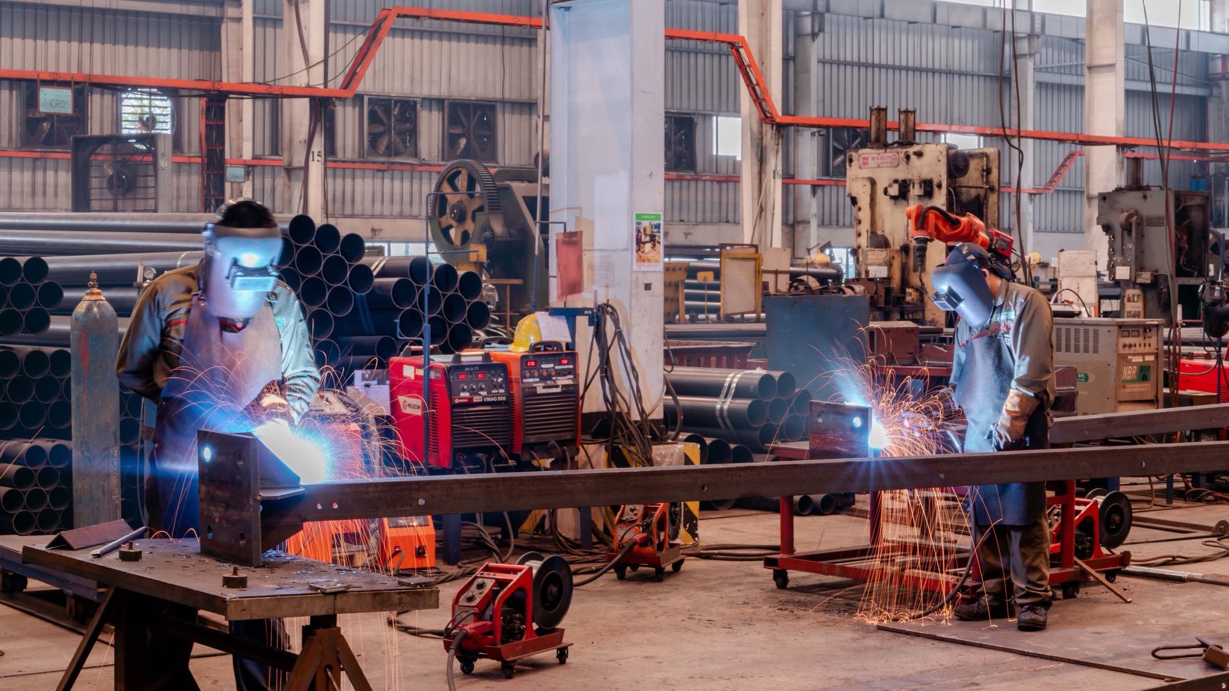 Soldadores trabajando en una nave de fabricación de acero en México, con chispas de soldadura — commerce B2B para manufactura